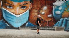Un hombre camina junto a un mural de homenaje a los sanitarios en Melide