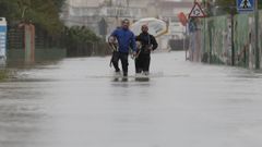 Dos hombres abandonan, con sus perros, la zona de la playa de Bellreguart, en Valencia.