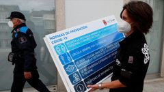 Una mujer coloca un cartel informativo en una calle de Viveiro
