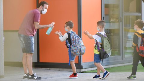 Fila de estudiantes echndose gel antes de entrar a su colegio en Laln