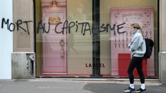 Una mujer pasa ante una pintada que reza  Muerte al capitalismo  en una tienda de Lyon