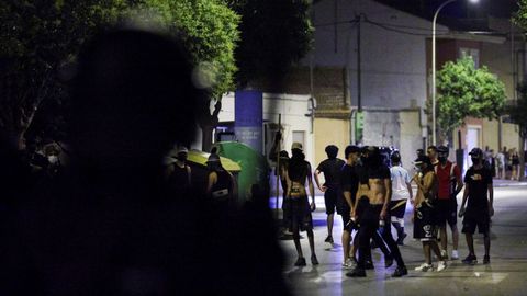 Un agente antidisturbios vigila a varios miembros de los grupos ultras reunidos en Torre Pacheco.