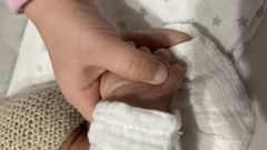 Imagen de archivo de una madre sujetando la mano de su hijo recin nacido.