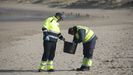 Dos operarios recogen p�lets de pl�stico en las playas de Asturias.
