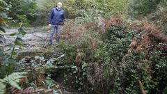 Roberto Y��ez, vecino de Xunqueira, en el puente de Cabandela, donde el agua puede hacer presa debido a la estrechez de los tubos por los que tiene que pasar el curso fluvial, y a la maleza