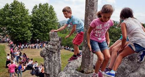 Unos nios juegan en las piedras del monte mientras los romeros asisten a la misa en los exteriores de la capilla, al fondo. 