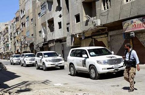 Un rebelde cruza delante del convoy de expertos de la ONU en el barrio de Zamalka, en Damasco.
