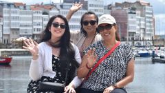 Tres turistas saludan a cámara en la zona de la Marina tras bajar del barco.