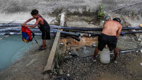 Venezolantos toman agua de una tuber�a abandonada ante la falta de electricidad y de suministro de agua potable