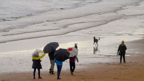 Paseantes por la playa de San Lorenzo, en Gij�n, en un d�a de lluvia