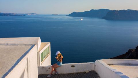Una turista disfruta de las vistas del mar Egeo en la isla griega de Santorini