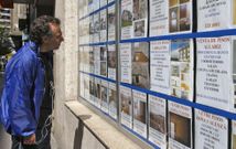 Un hombre observa los anuncios en el escaparate de una inmobiliaria de la capital ourensana. 