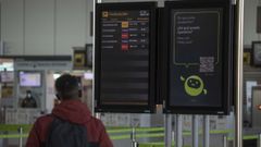 En una imagen de archivo, un panel de información de vuelos y el control de pasajeros en el aeropuerto Rosalía de Castro de Santiago
