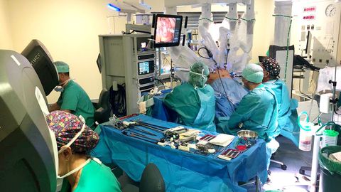 Una operaci&oacute;n con el robot Da Vinci en el Hospital &Aacute;lvaro Cunqueiro; a la derecha se ven los brazos del robot, y a la izquierda, dos consolas con cirujanos