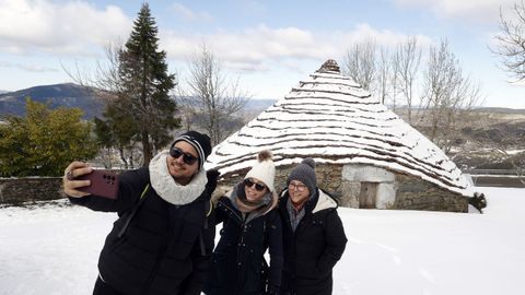 Un grupo de jvenes se fotografan junto a una palloza nevada en O Cebreiro, en una imagen de este febrero