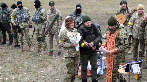 Los miembros de las Fuerzas de Defensa Territorial de Ucrania, Lesia Ivashchenko y Valerii Fylymonov, escuchan a un sacerdote en su boda durante el conflicto Ucrania-Rusia, en un puesto de control en Kiev, Ucrania.