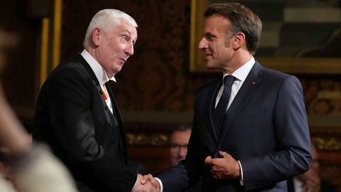 Emmanuel Macron le estrecha la mano a Lindsay Hoyle, el presidente de la Cámara de los Comunes.