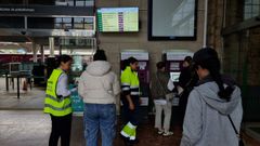 Operarias ayudan a varios pasajeros a utilizar las mquinas de autoventa en la estacin de tren de Ourense