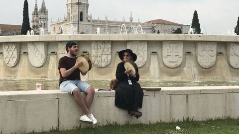 El personaje de la ciega y uno de los m�sicos de la Bandina L�mbolau tocan la panderera con el Monasterio de los Jer�nimos al fondo