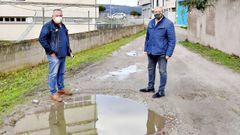 Los populares Soto y Rodr�guez, ante una de las fochancas del vial que piden pavimentar