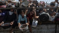 Un grupo de gazates desplazados a Yan Junis esperan a recibir comida en una  cocina benfica