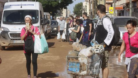 Un hombre transportando un carro de la compra en Valencia tras los daos causados por la dana