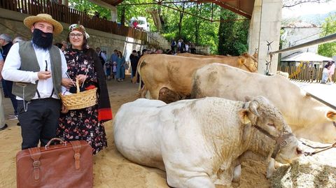 Dos vecinos vestidos de poca junto a una de las reses expuestas en la feria de este domingo en Seoane do Courel