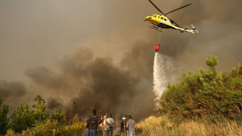 Un helicptero descarga agua ayudando a las labores de control de los vecinos en Quins y Vilaverde, enMeln