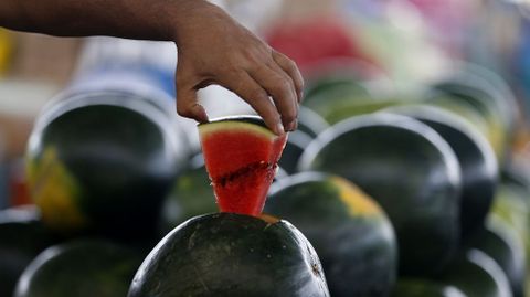 Un hombre coge una pieza de sandía en un mercado de Dubai