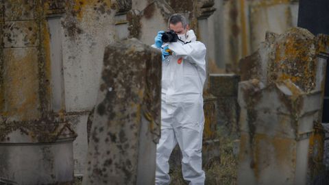 Un investigador toma foto de una de las tumbas que objeto de las pintadas