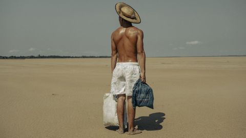 La sequía obliga a un joven a caminar dos kilómetros para poder llevarle comida a su madre. Al pueblo de Manacapuru se podía llegar en barco, pero ahora tiene que desplazarse andando a través del lecho del río Solimoes, en el Amazonas en Brazil
