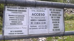Cartel informativo en la valla de un camino que conduce a los petroglifos