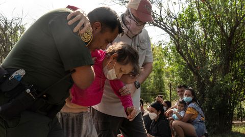 Irma, de 80 a�os, es ayudada por un oficial de migraci�n y otro hombre.