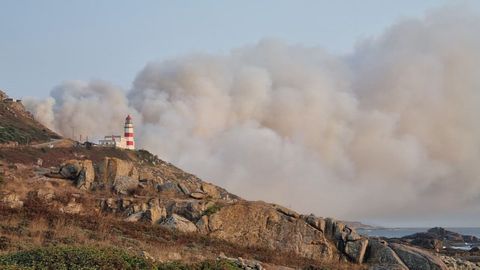 El faro-hotel de Cabo Silleiro junto a la nube de humo del incendio de Mougás