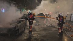 Los bomberos extinguen el fuego de los coches quemados en Bilbao.