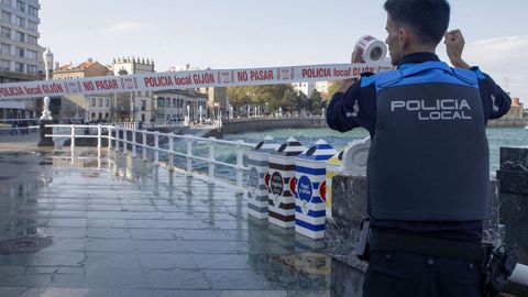 Un policía cierra un tramo del paseo marítimo de San Lorenzo, en Gijón