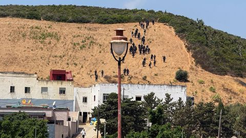 Agentes de la polic�a y la gendarmer�a marroqu�es, acompa�ados por fuerzas auxiliares equipadas con material antidisturbios, descienden una colina tras impedir un intento de cruce fronterizo de migrantes hacia Espa�a en Fnideq, Marruecos.