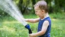 Un niño sujeta una manguera de agua