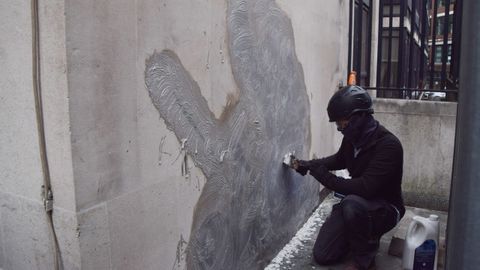 Un trabajador limpia una de las obras de Banksy en Londres