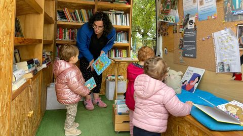 La bibliotecaria de la Furgoteca muestra cuentos a tres nias de O Incio