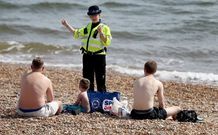 Una agente brit�nica invita a unos ba�istas a abandonar el arenal de Brighton, en el sur de Inglaterra