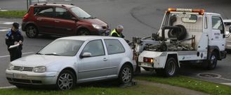 Un polic�a local multa un coche mal aparcado mientras lo retira la gr�a. 