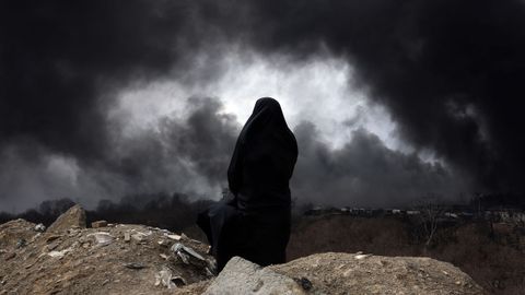Una mujer observa el humo que se desprende de la refiner�a de Shahran, debido al incendio que han provocado los ataques israel�s de esta noche.