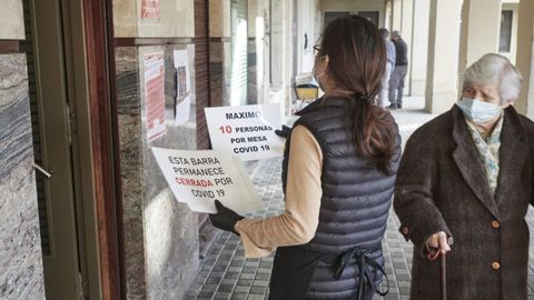 Una camarera coloca carteles de reducci�n de aforo en Pamplona