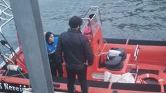 Sara P�rez durante la llegada a puerto tras haber ca�do al agua al rescatar a uno de los ni�os arrastrados por la marea en Luarca. De espaldas, el patr�n Carlos Rodr�guez