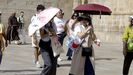 Turistas protegiéndose del sol con paraguas en Santiago de Compostela