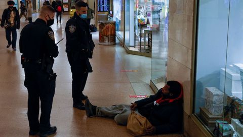 Unos agentes se dirigen a un sintecho en el metro de Nueva York