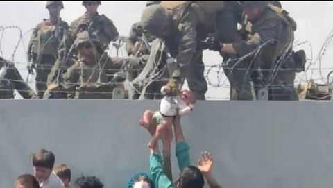 Un soldado estadounidense recoge a un beb� en la valla de la terminal del aeropuerto de Kabul, durante la ca�tica evacuaci�n. 