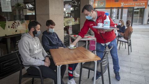Toni Chaves sirve a unos clientes en la terraza de su cafeter�a, en Boiro
