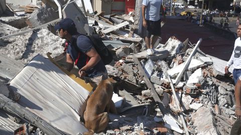 Personas caminan entre los escombros de un edificio
